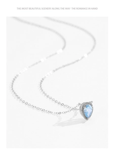 Detailed close-up of a silver necklace with a teardrop blue gemstone and beaded edge detail