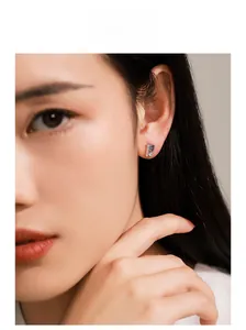 Macro view of S925 silver flower stud earring with blue and clear gemstones on ear