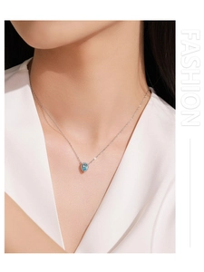 Close-up of elegant 925 silver necklace with pear-shaped light blue gemstone on neck