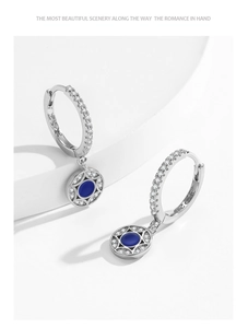 Macro detail of S925 sterling silver hoop earrings with blue stone and starburst charm