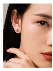 Close-up of S925 silver stud earring with blue-purple gemstone on a model's ear