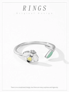 Macro detail of 925 sterling silver open ring featuring enamel bee and green leaf design