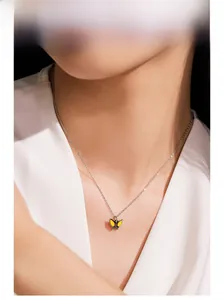 Detail of a minimalist 925 sterling silver necklace with a yellow butterfly pendant on a model