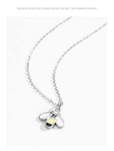 Vue macro du pendentif abeille en argent avec ailes blanches et détails en émail jaune