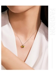 Gros plan du collier avec pendentif papillon en émail jaune sur une chaîne en argent