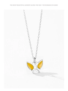 Gros plan d'un collier en argent sterling 925 avec un pendentif papillon en émail jaune vif