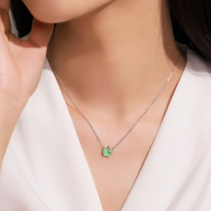 Sterling silver necklace featuring a green enamel apple pendant on a model's neck