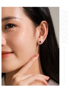 Close-up of 925 sterling silver red heart enamel studs worn on a model ear
