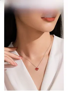 Gros plan du collier cœur en émail rouge avec zircon en étoile sur chaîne argent