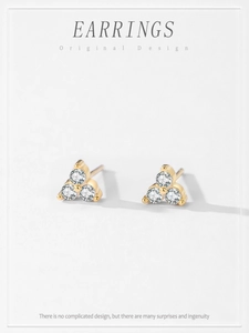 Macro view of gold 925 silver triangle stud earrings with micro-pave cubic zirconia crystals