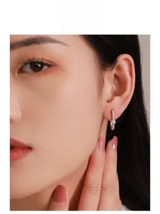 Gros plan d'une boucle d'oreille en U en argent sertie de diamants sur une oreille de mannequin