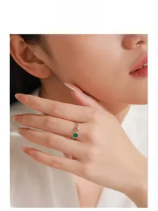 Close-up of 925 sterling silver heart ring featuring a green emerald gem on a model hand