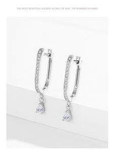 Close-up of 925 sterling silver U-shaped earrings with hanging pear-cut diamonds