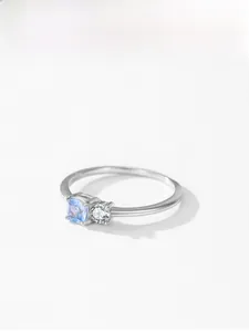 Macro shot of S925 silver ring featuring blue princess-cut and white round stones
