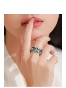 Close-up of stacked 925 silver rings with blue and green marquise-cut stones on a finger