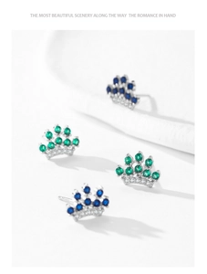 Detailed macro of 925 sterling silver crown earrings with emerald green and blue zircon