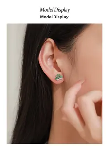 Close-up of crown stud earring with green zircon and silver base on model's ear