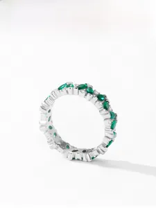 Detail of silver eternity ring featuring marquise emerald stones and round diamonds