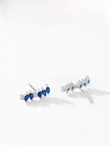 Macro shot of S925 silver curved earrings with blue marquise zircon and small white diamonds