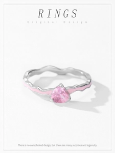 Detail of wavy silver ring with pink heart zircon and enamel trim on light background