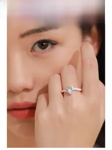 Gros plan d'une bague en émail rose avec pierre de cœur étincelante au doigt
