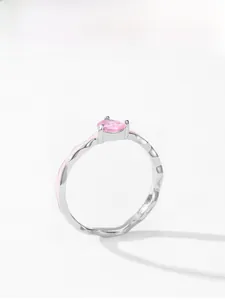 Detail of silver ring with pink heart zircon and wavy enamel band on white background