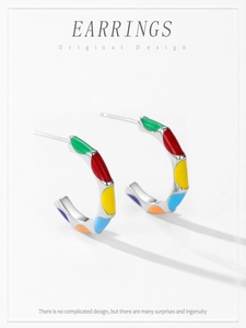 Macro detail of 925 silver C-shaped stud earrings with colorful enamel wave patterns