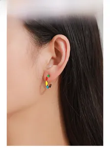 Close-up of model wearing colorful enamel C-shape earrings with geometric artistic design