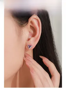 Gros plan d'une boucle d'oreille triangle en argent S925 avec zircon violet portée