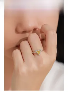 Close-up of a 925 sterling silver ring with a yellow triangle gemstone on woman finger
