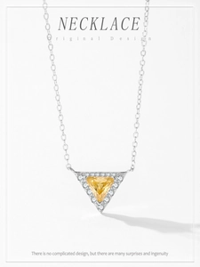 Macro view of a gold-plated triangle pendant necklace with a yellow cubic zirconia stone