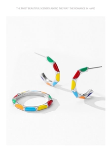 Macro detail of S925 silver C-shape earrings and ring with vibrant rainbow enamel blocks