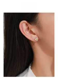 Detail of model wearing a 925 silver earring with a triangular yellow gemstone and halo