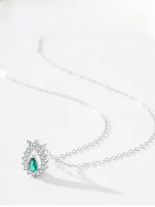 Vue macro du pendentif émeraude zircon avec détail de collier en argent ajouré