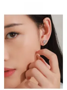 Macro detail of silver butterfly wing earring with pink teardrop stone on model