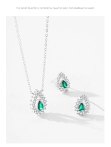 Detailed view of pear-shaped green emerald earrings and necklace set with silver accents