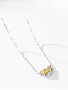 Detail view of crescent yellow gemstone pendant with white diamond pave on silver chain
