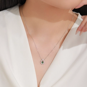 Collier en argent 925 avec goutte d'émeraude porté par un mannequin élégant