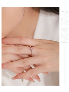 Detailansicht eines Silberrings mit rundem rosa Edelstein am Finger einer Frau