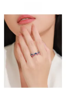 Détail d'une bague trèfle en argent élégante avec cristaux bleus et roses portée au doigt