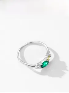 Detail of silver ring with oval emerald gemstone and yellow pear-shaped side stones