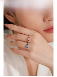 Détails de bagues en argent 925 avec pierres roses et bleues sur le doigt du modèle