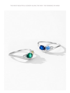 Macro shot of silver rings with emerald and sapphire stones on white background
