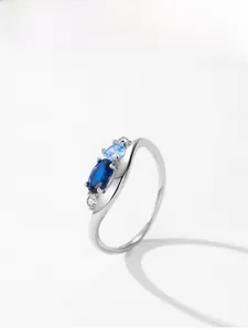 Detail view of wavy silver ring featuring dark blue oval and light blue round gemstones