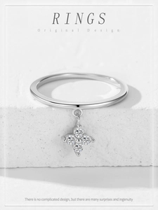 Detailed view of sterling silver ring with clover pendant on white textured stone display