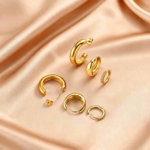 Detailed close-up of gold stainless steel hoop earrings set with zircon on silk