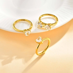 Three-piece gold stainless steel ring set with heart-shaped zircon stones on a white plate