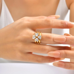 Detail of gold clover ring set with heart-shaped cubic zirconia worn by a model