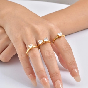 Close-up of three gold stainless steel rings with heart-shaped zircon stones on hand