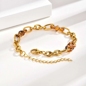Gros plan du bracelet à maillons dorés avec perles en résine ambre sur fond blanc